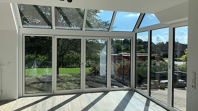 Innenansicht eines angebauten Wintergarten mit Blick in den Garten